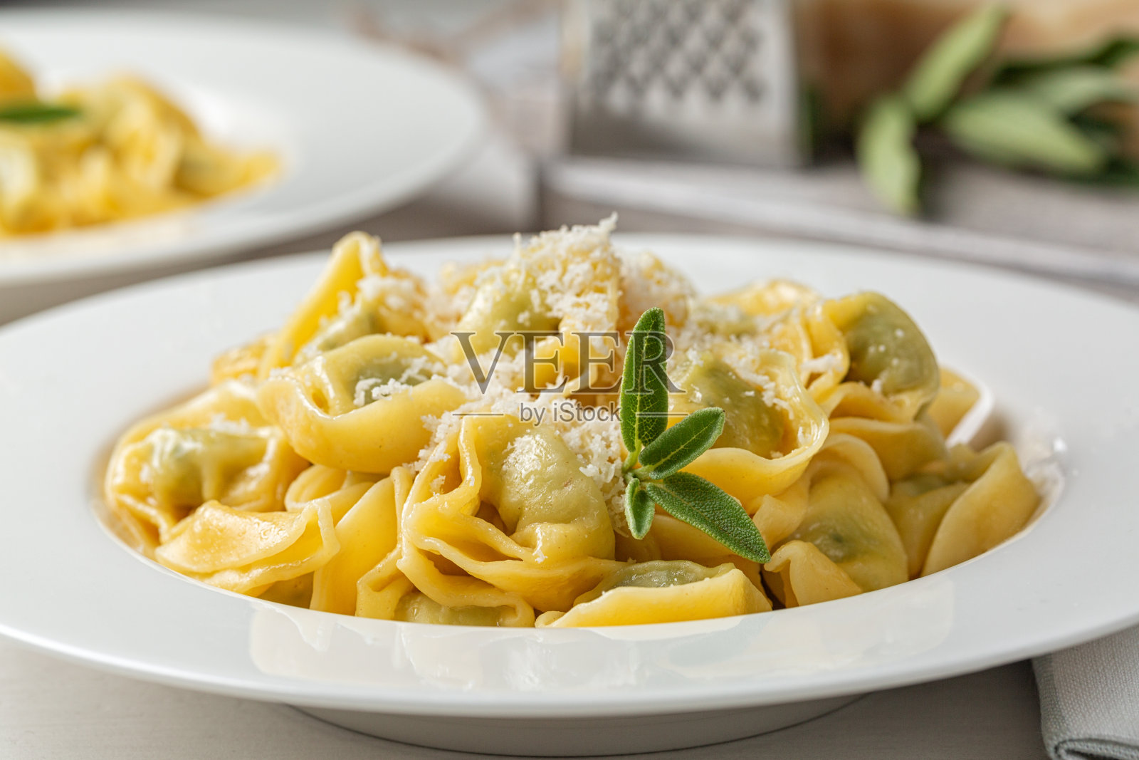 特写的意大利通心粉塞满了菠菜和乳清干酪，用融化的黄油和鼠尾草叶炒。磨碎帕尔马干酪。照片摄影图片