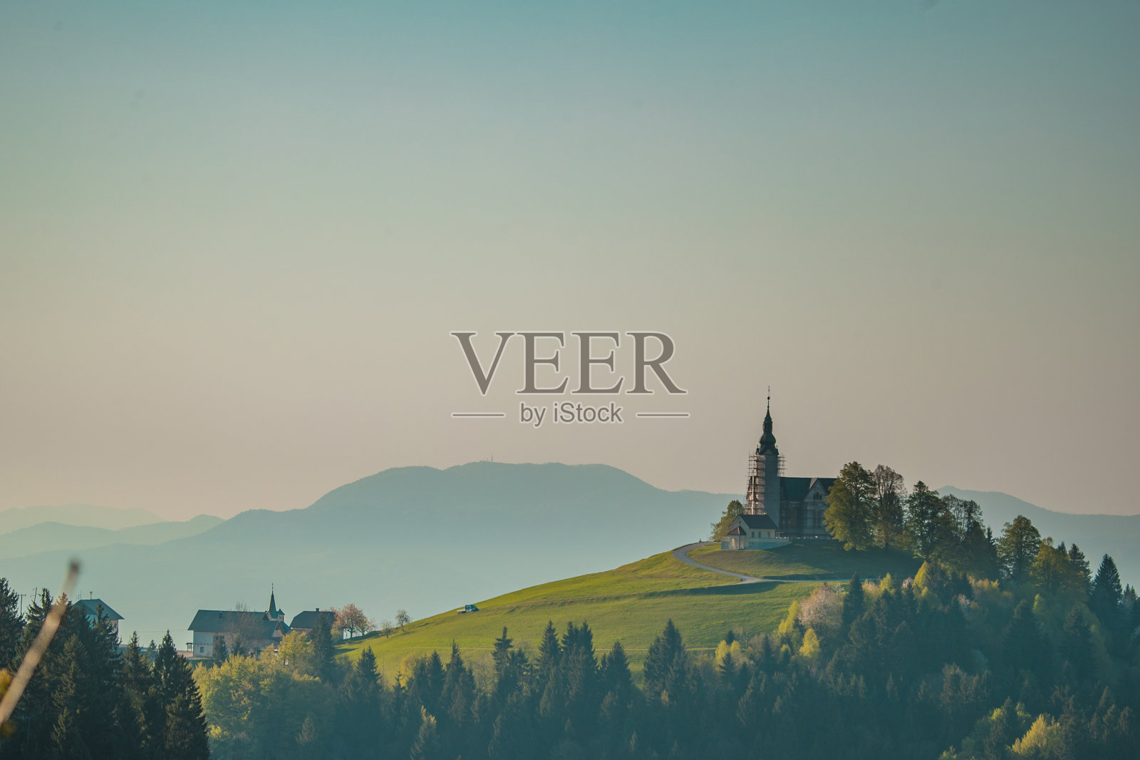 斯洛文尼亚Crni Vrh风景如画的小教堂，日出时分。钟楼周围有金属脚手架，正在翻新。照片摄影图片