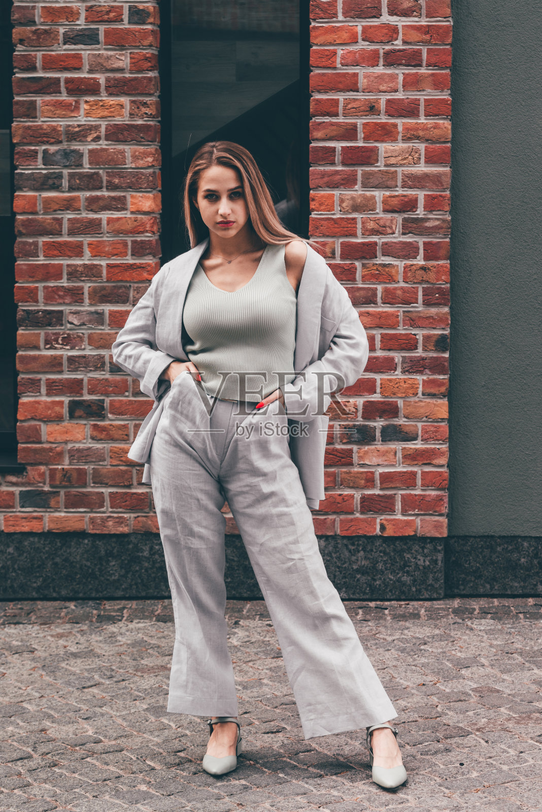 一个金发的时尚女人穿着蓝色的棉套装在街上摆姿势。夏装风格时尚照片摄影图片