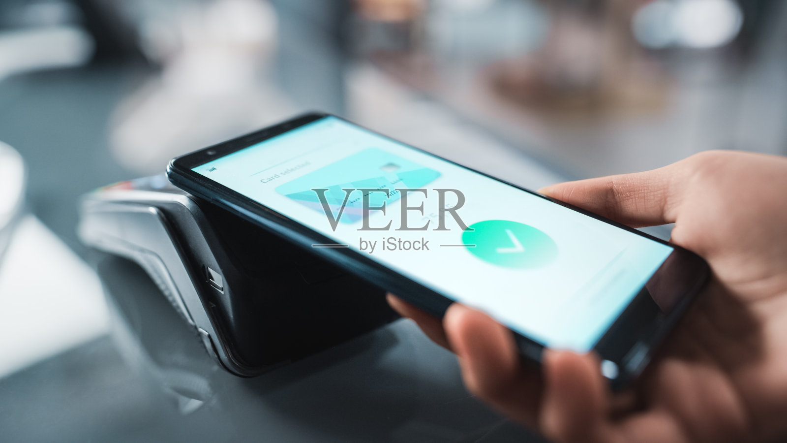 服装店:柜台顾客用智能手机通过非接触式NFC银行终端付款购买衣服。时尚时尚商店与时尚设计师品牌。近距离聚焦手部。照片摄影图片