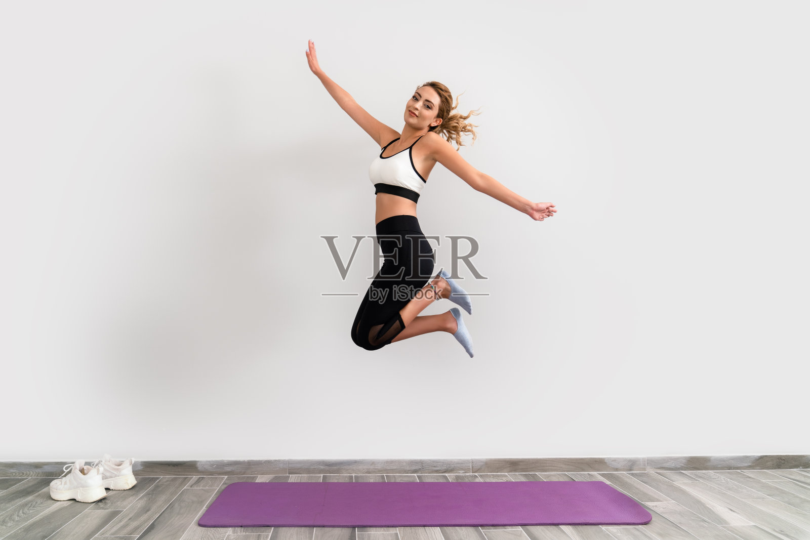 美丽的女人在普拉提垫上跳得很高，为健美的身体和健康的生活做锻炼照片摄影图片