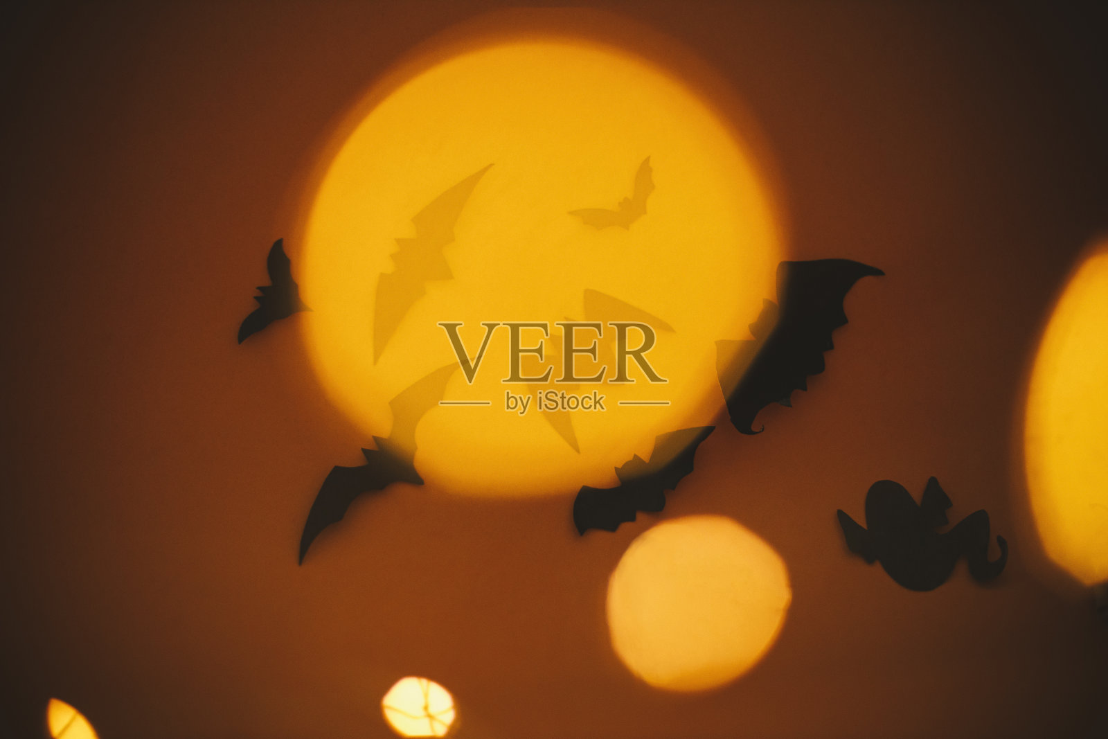 万圣节快乐。蝙蝠在暗橙色的背景上飞行，带着魔法灯散景。万圣节大气背景。节日的邪恶幽灵装饰。不给糖就捣蛋照片摄影图片