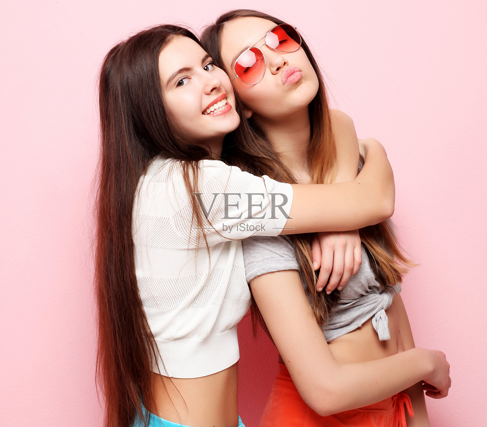 快乐微笑的漂亮少女或朋友拥抱粉红色照片摄影图片