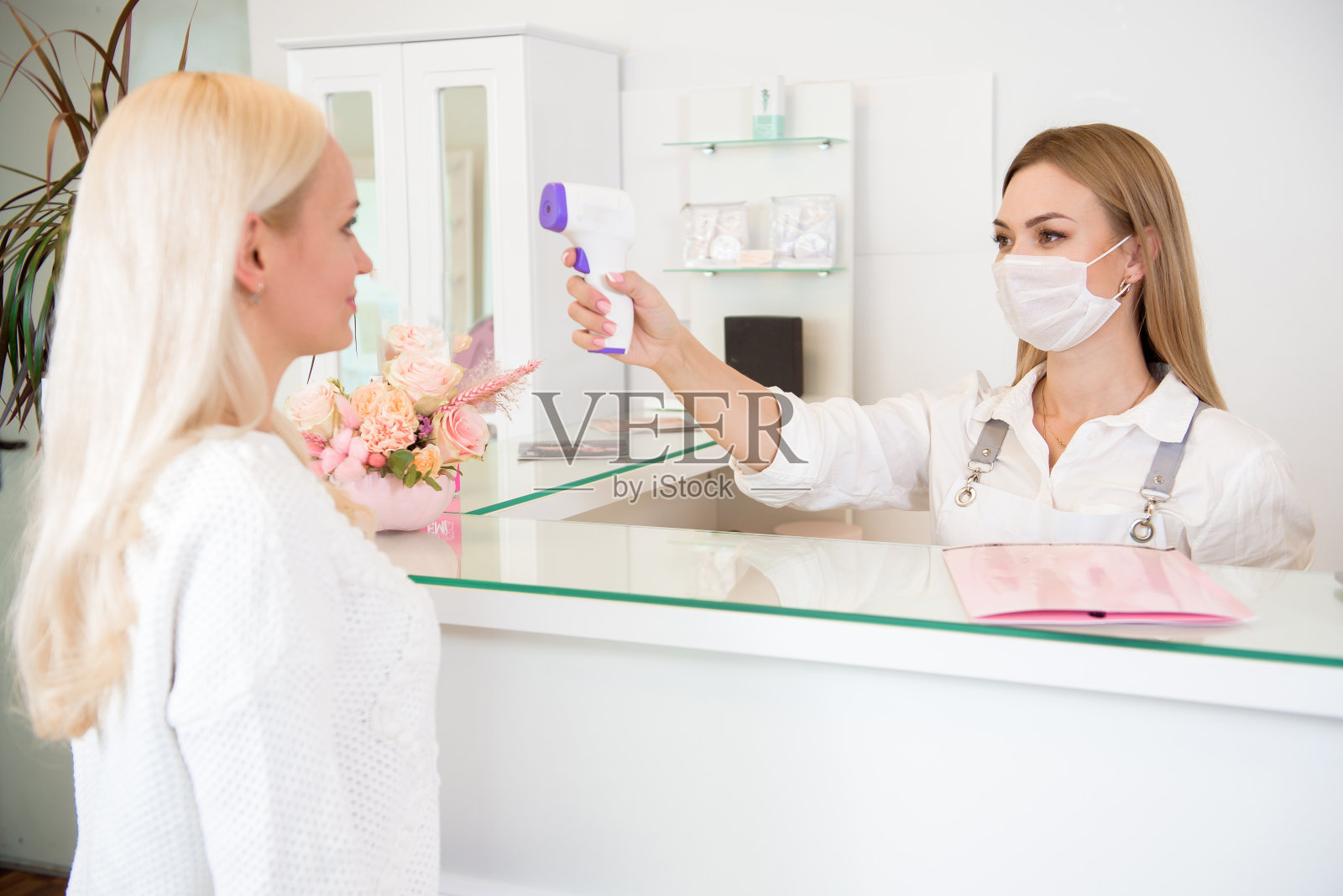 疾病控制，使用红外温度计设备检查温度在水疗沙龙。照片摄影图片