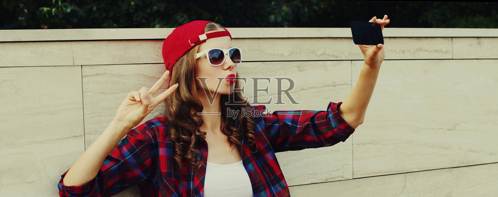 一名少女戴着棒球帽在城市里用智能手机自拍照片摄影图片