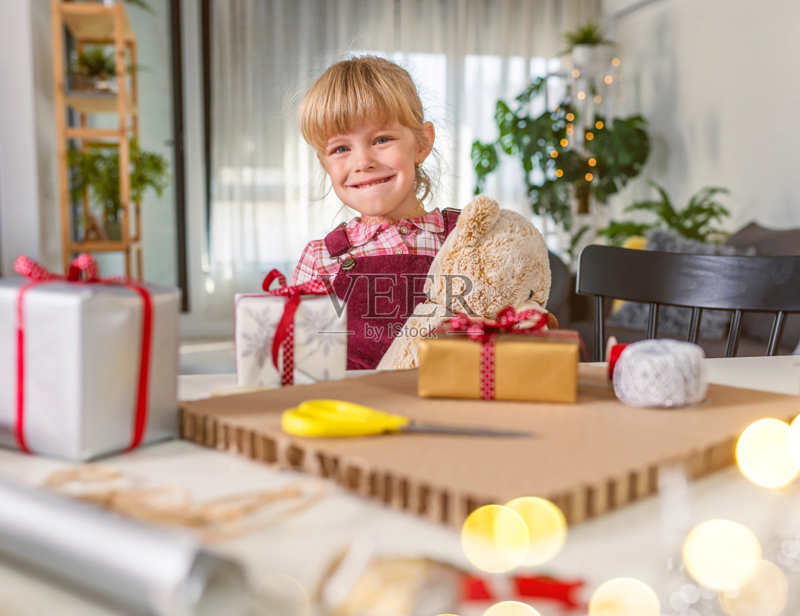 可爱的小女孩抱着泰迪熊微笑，对节日和礼物感到开心照片摄影图片