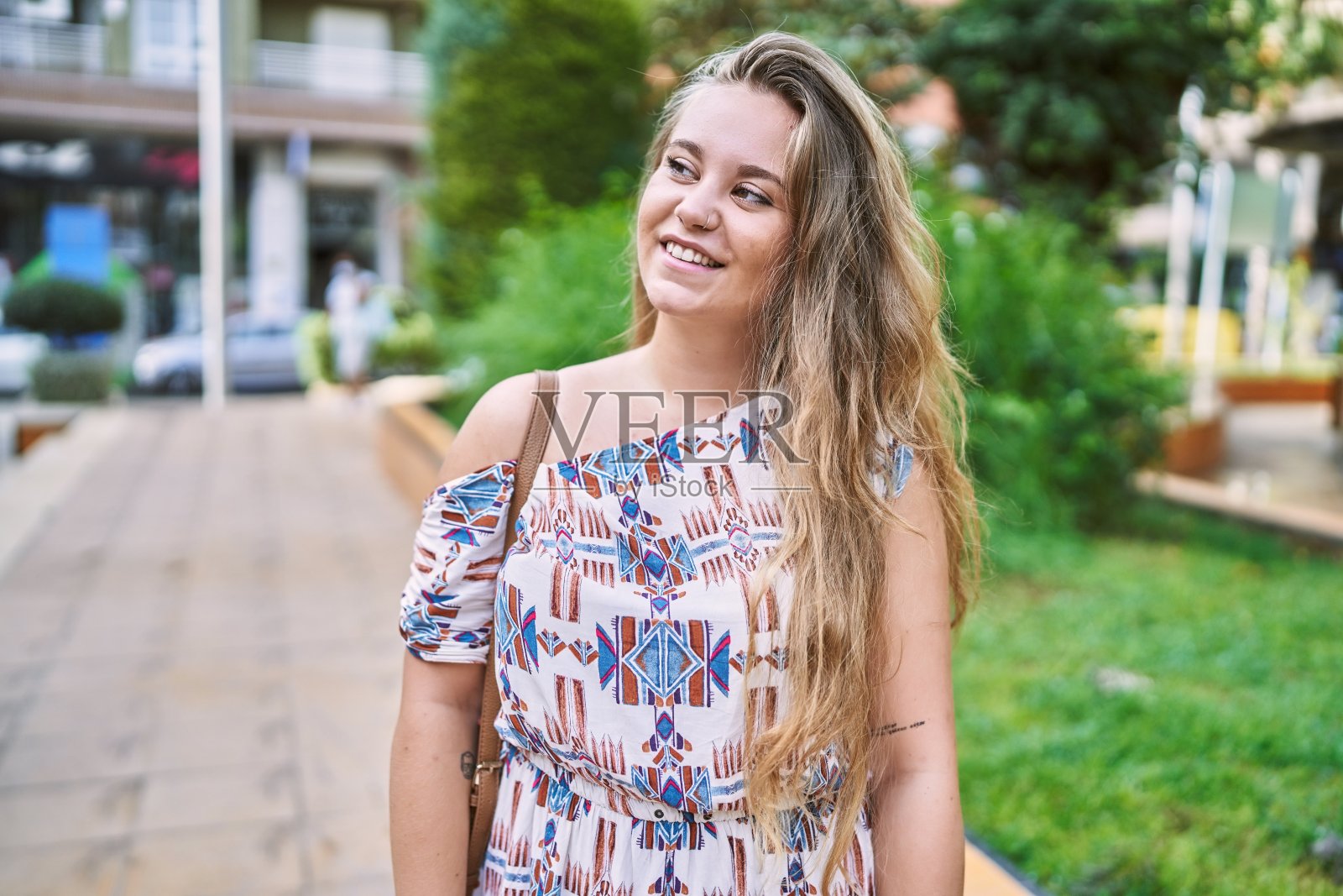 年轻的金发女孩微笑着幸福地站在城市。照片摄影图片