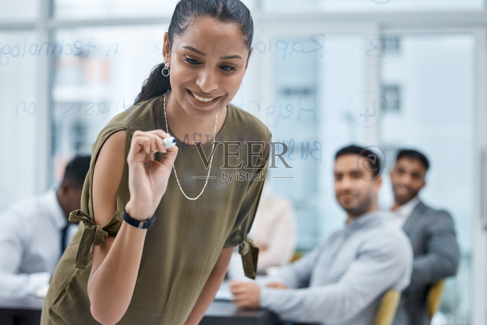 一个年轻的女商人在办公室开会时在玻璃屏幕上写笔记照片摄影图片