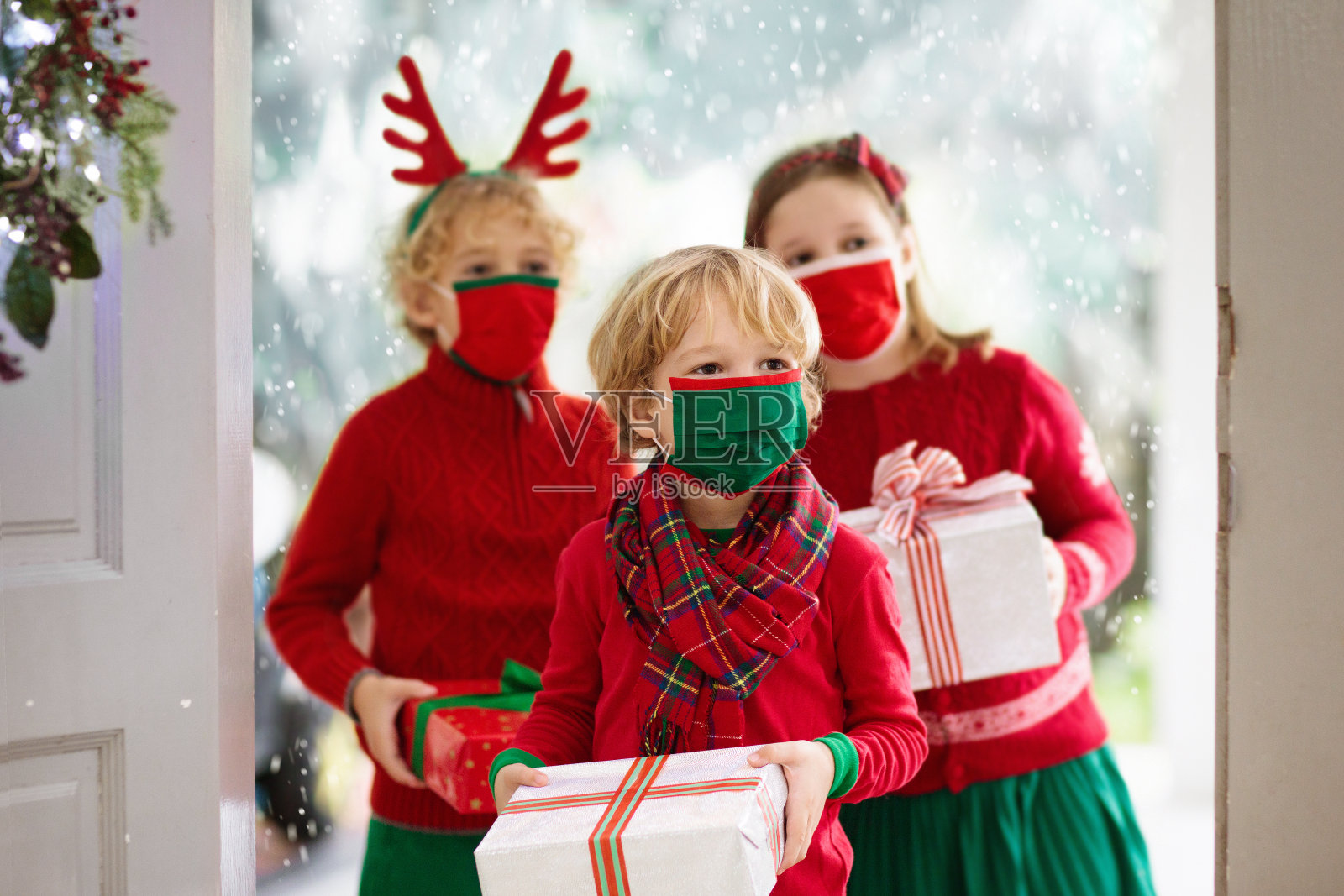 家人在圣诞节。孩子们在门口拿着礼物。照片摄影图片
