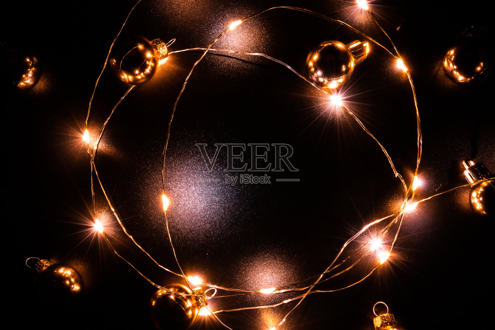 圣诞灯。金光花环装饰，金色灯泡孤立在黑色为圣诞派对装饰背景。圣诞节的灯火辉煌。照片摄影图片