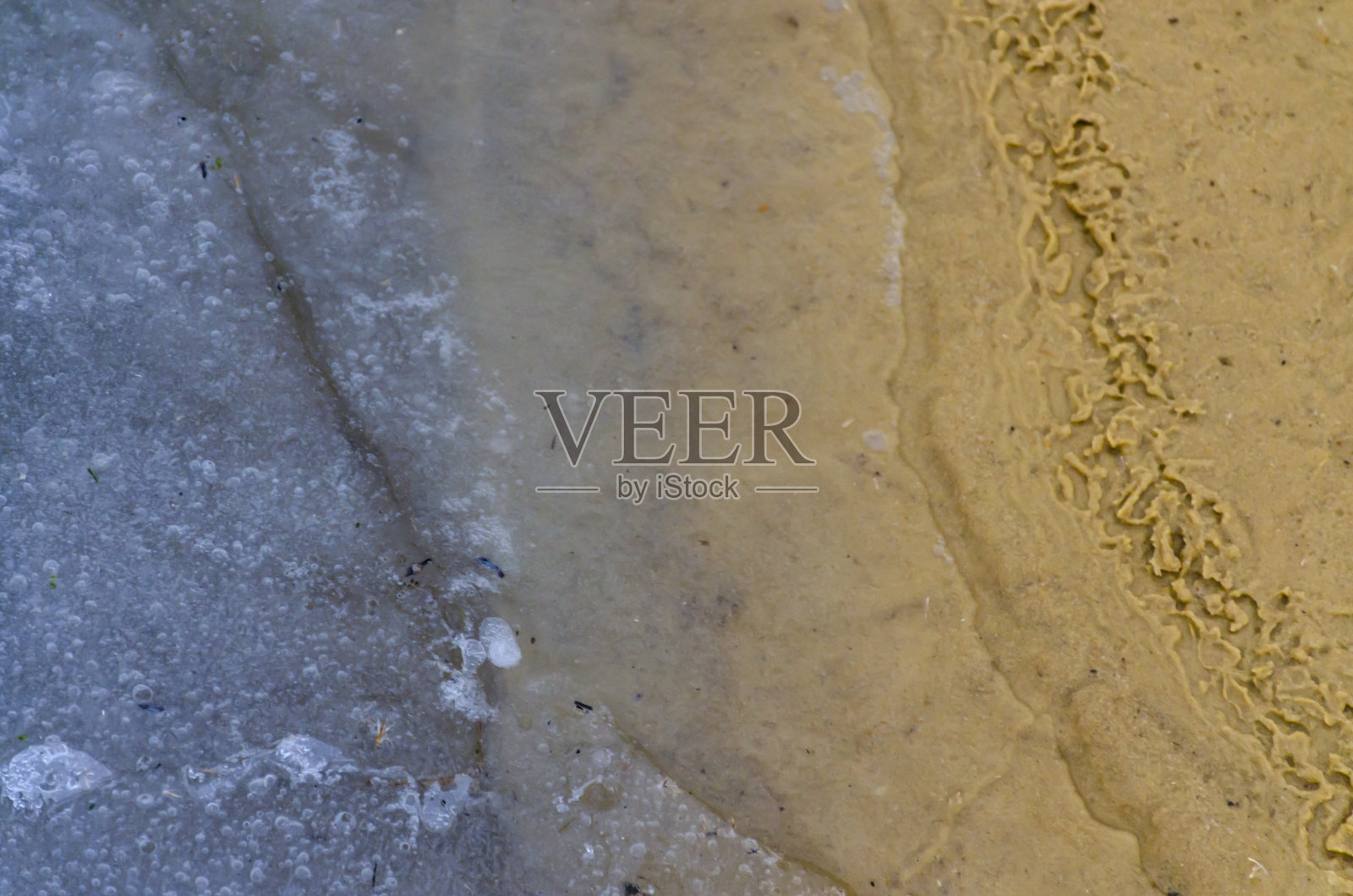 冰冷的冰覆盖了海滩上的沙子。寒冷的冬天的概念。水库的冻结。靠近沙子和冰的纹理照片摄影图片