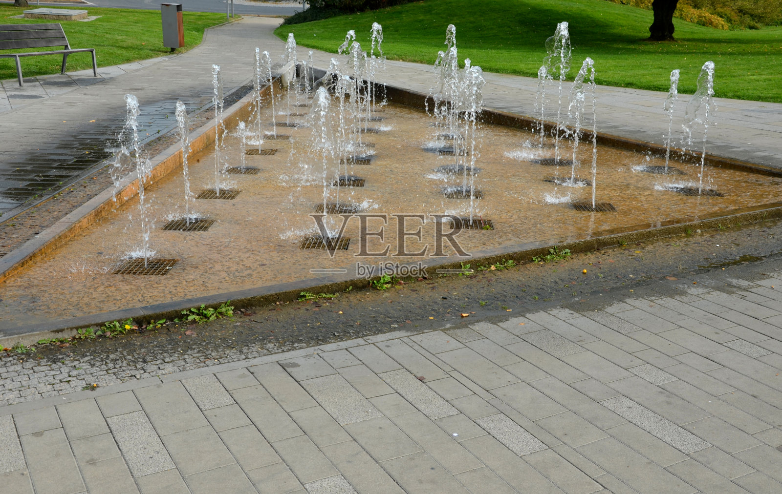 一个三角形，水按规则的排飞溅，水在射流中从网格中向上飞。随着音乐节拍的变化而变化。夏天，孩子们喝了水珠就神清气爽照片摄影图片