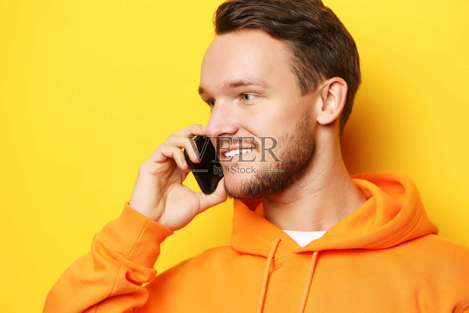 快乐的年轻人在黄色背景下讲手机照片摄影图片