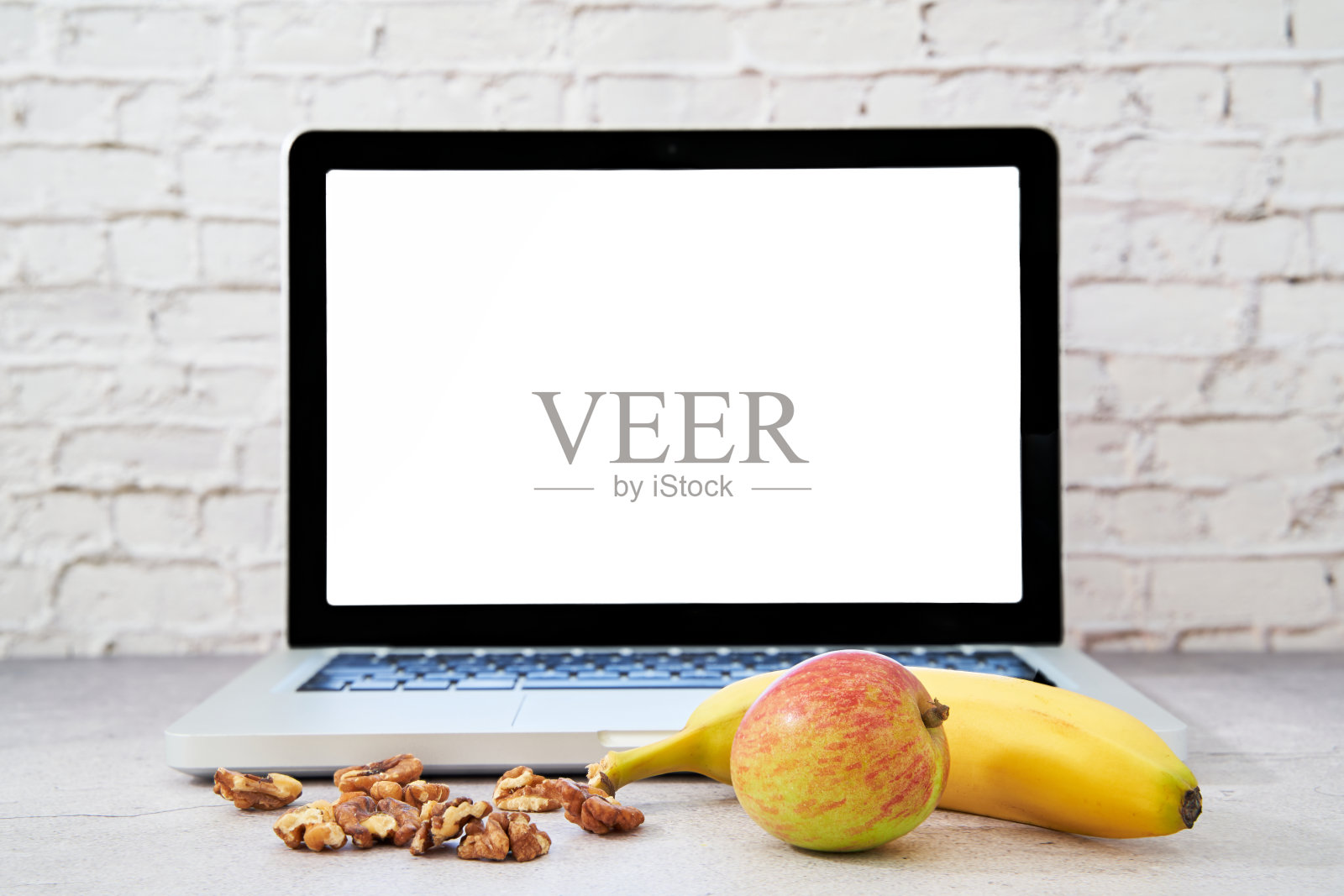 笔记本电脑前的健康食品。为文本留出空间。用苹果、香蕉和坚果作为健脑食物。照片摄影图片