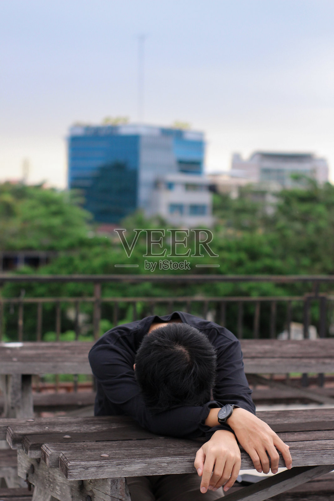 年轻人坐在城市公园里睡觉照片摄影图片