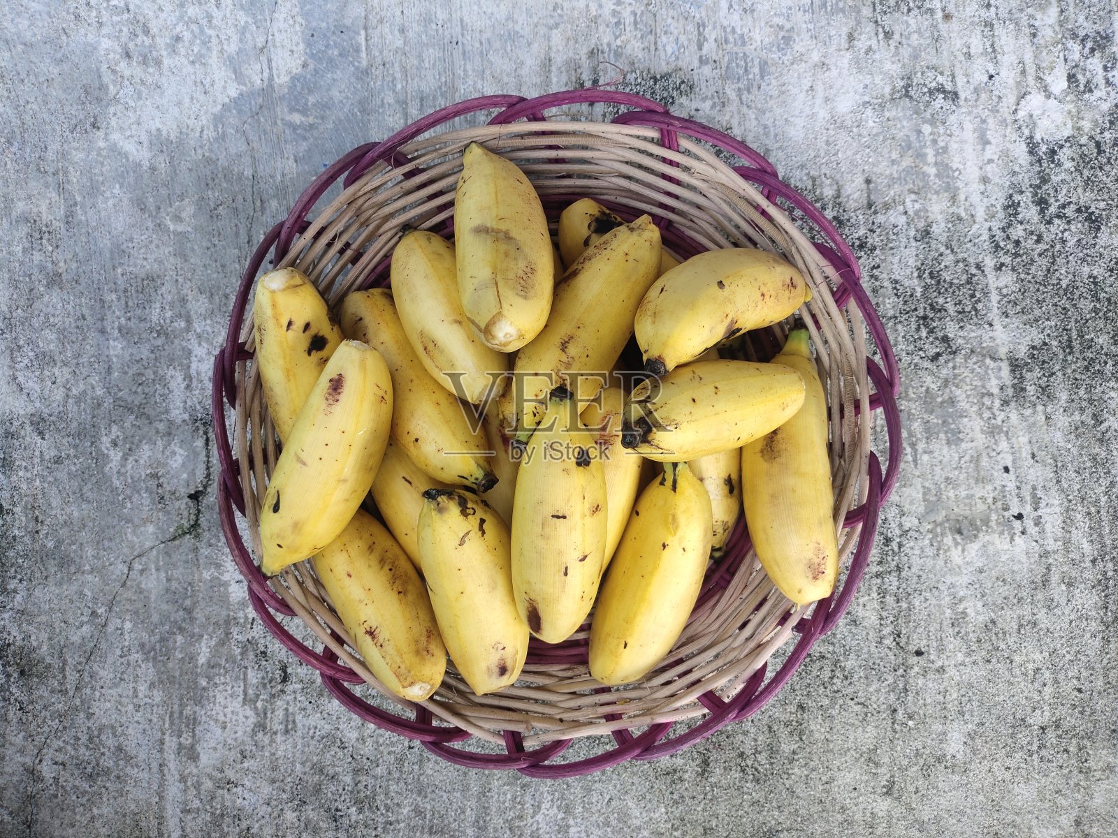 一堆小香蕉放在竹编上，孤立地放在混凝土地板上照片摄影图片