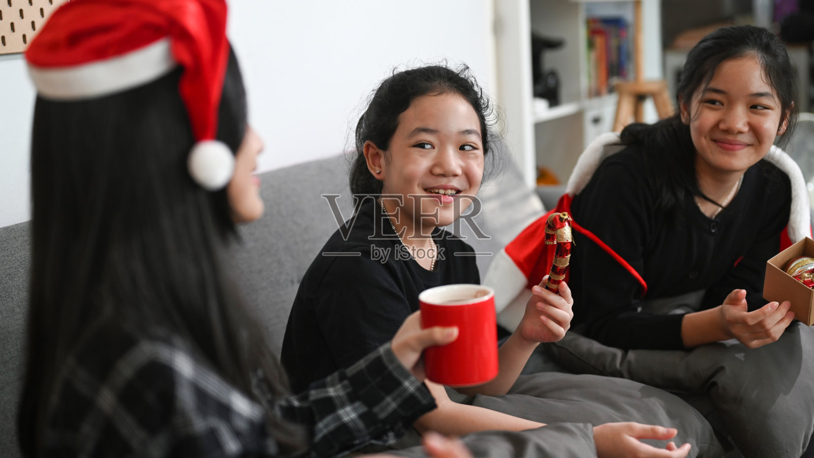 三个亚洲孩子在家里一起庆祝圣诞节。照片摄影图片