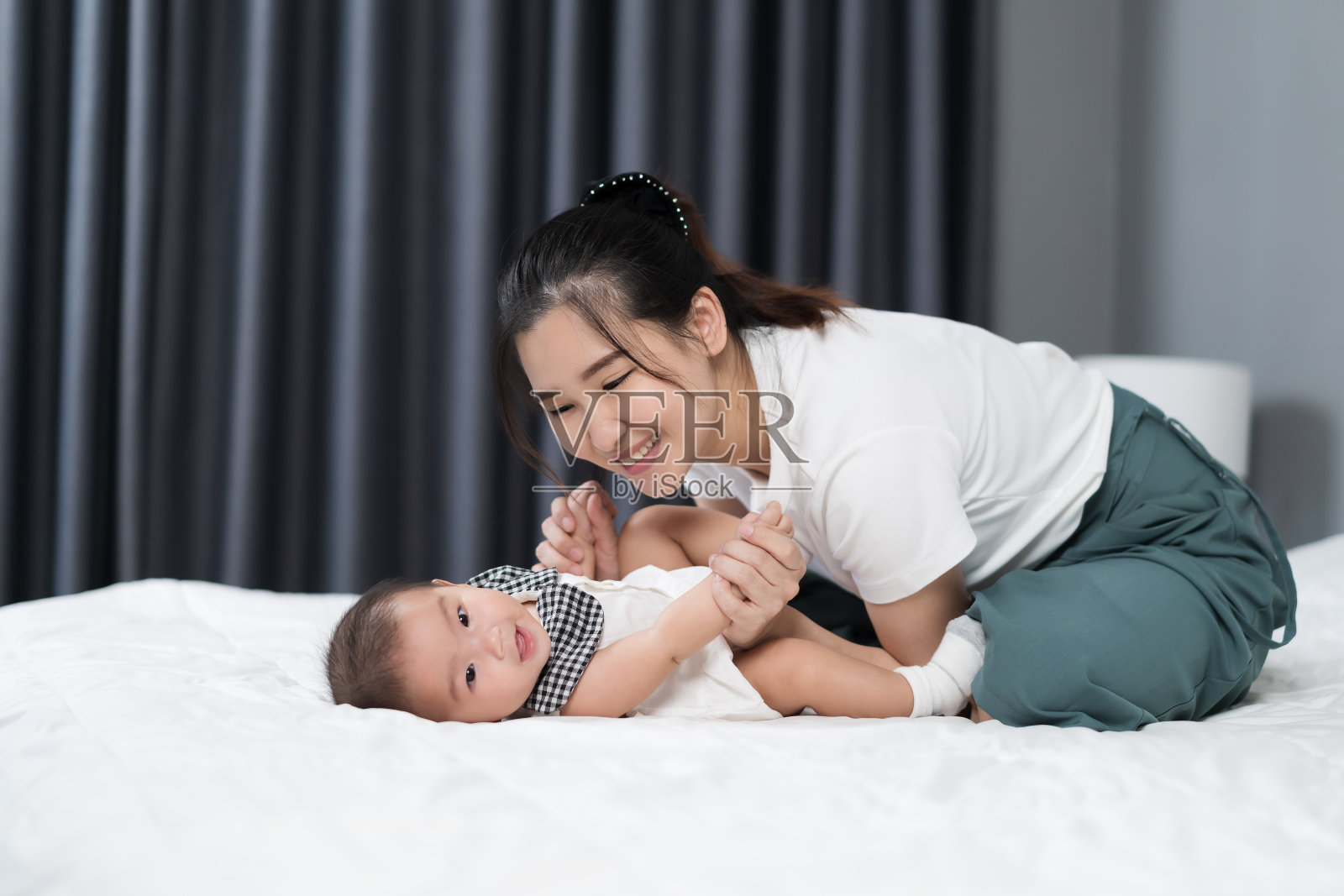 快乐的妈妈和宝宝在家里的床上玩耍照片摄影图片