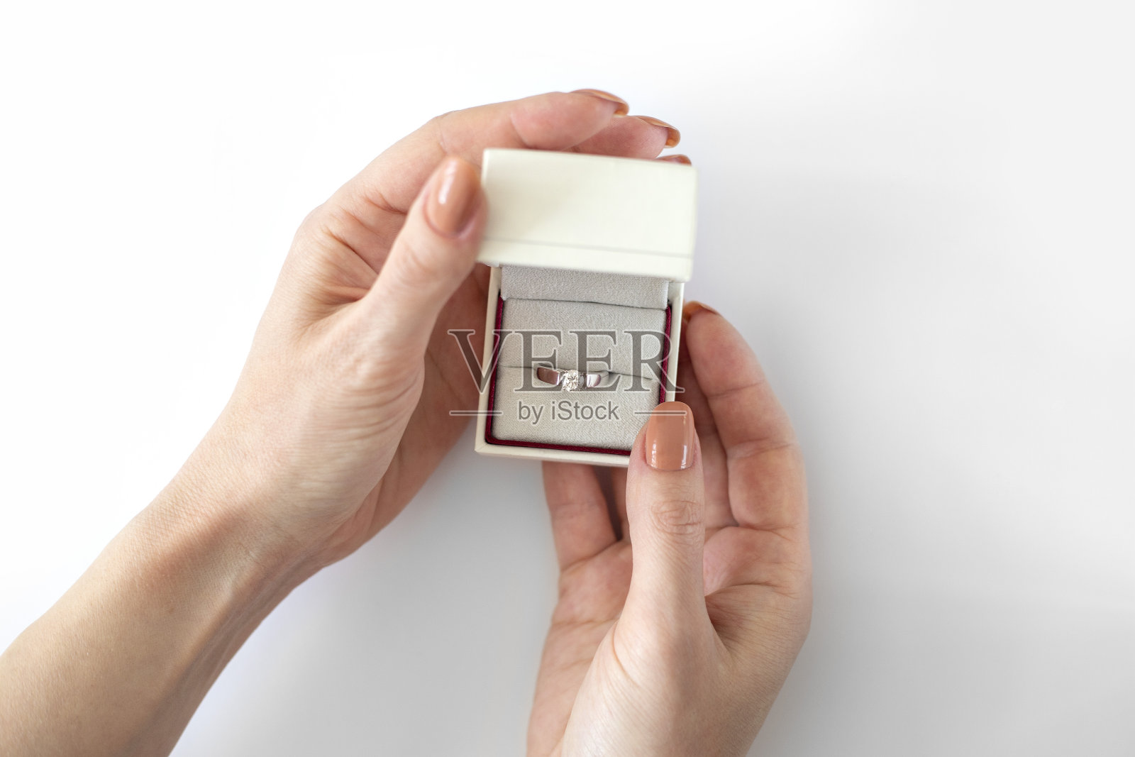 女性手打开白色的盒子，白色的背景上有钻石戒指。求婚结婚。白色盒子里的订婚钻戒照片摄影图片