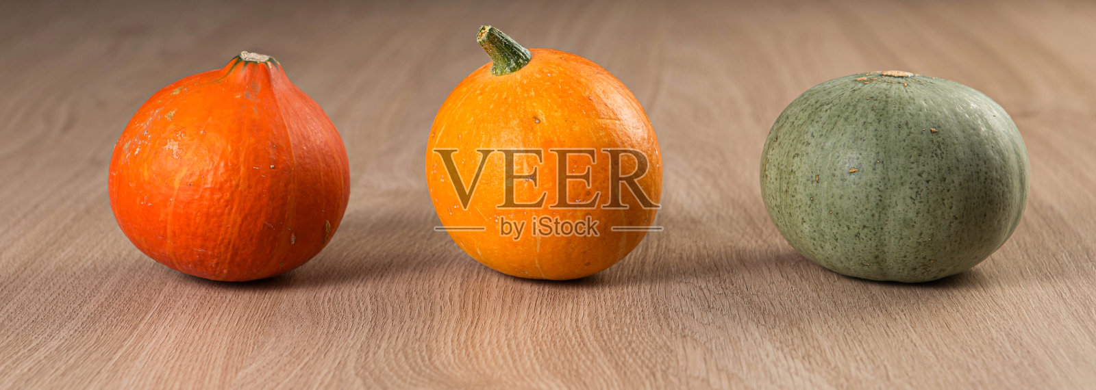 木桌上一排新鲜的南瓜，挂着条幅。感恩节和万圣节的节日概念。照片摄影图片