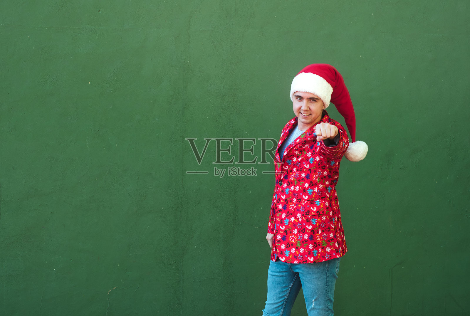 穿着圣诞主题衣服的男人微笑着直指照片摄影图片