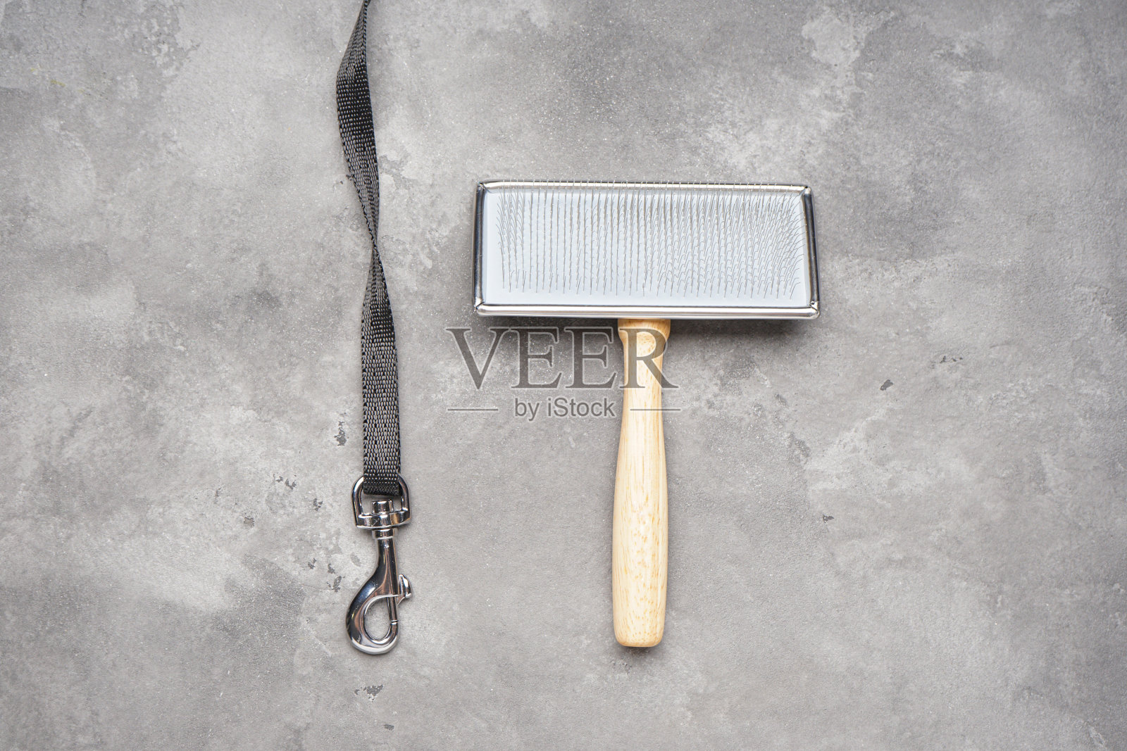 带钩环和梳刷的狗链在灰色背景。平的。照片摄影图片