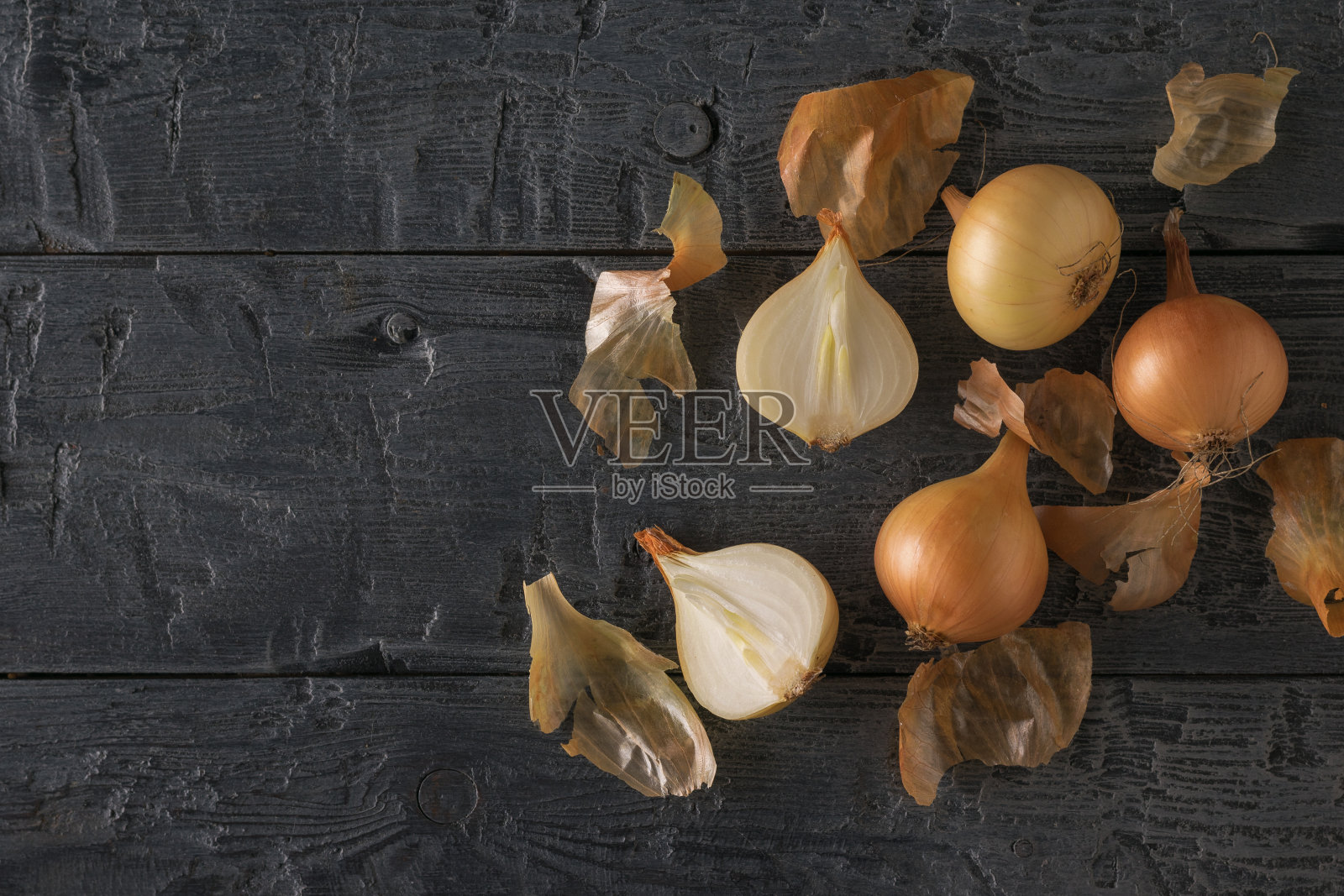 木桌上摆着剥皮和未剥皮的新鲜洋葱。照片摄影图片