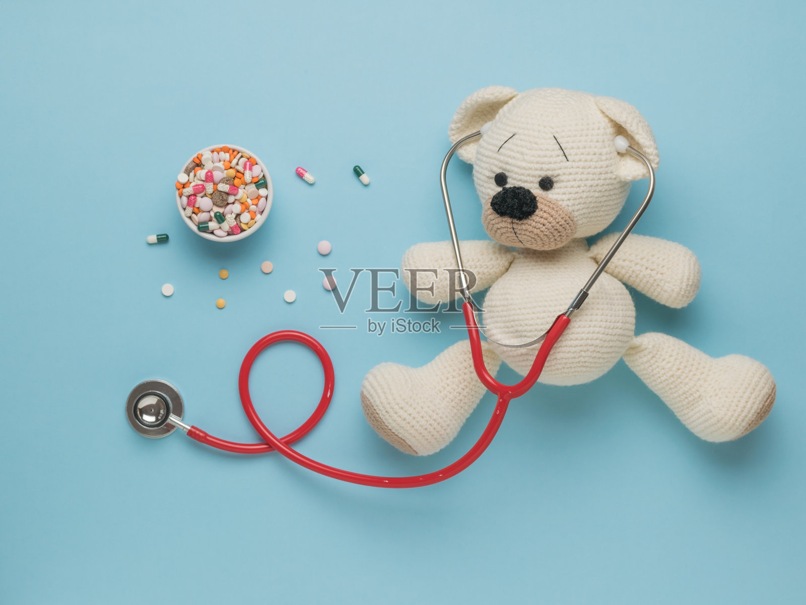 蓝色背景上的针织熊和大量药物的俯视图。照片摄影图片