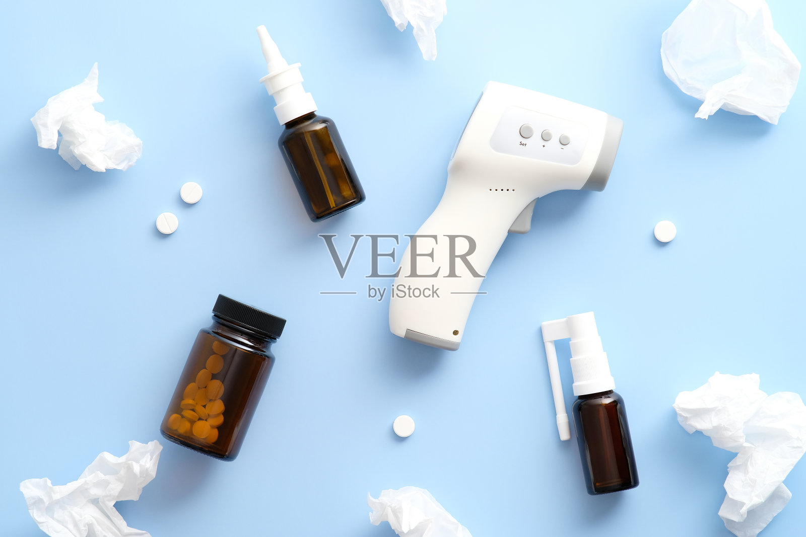 平铺构图与医疗数字红外温度计，药丸，喷雾剂，鼻滴，面巾纸在柔和的蓝色背景。Covid-19，冠状病毒治疗概念。照片摄影图片