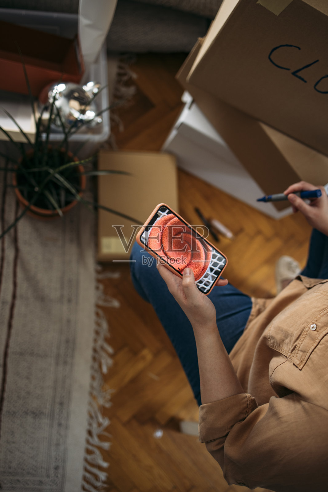 搬进来:匿名大号女人坐在地板上用手机浏览互联网照片摄影图片