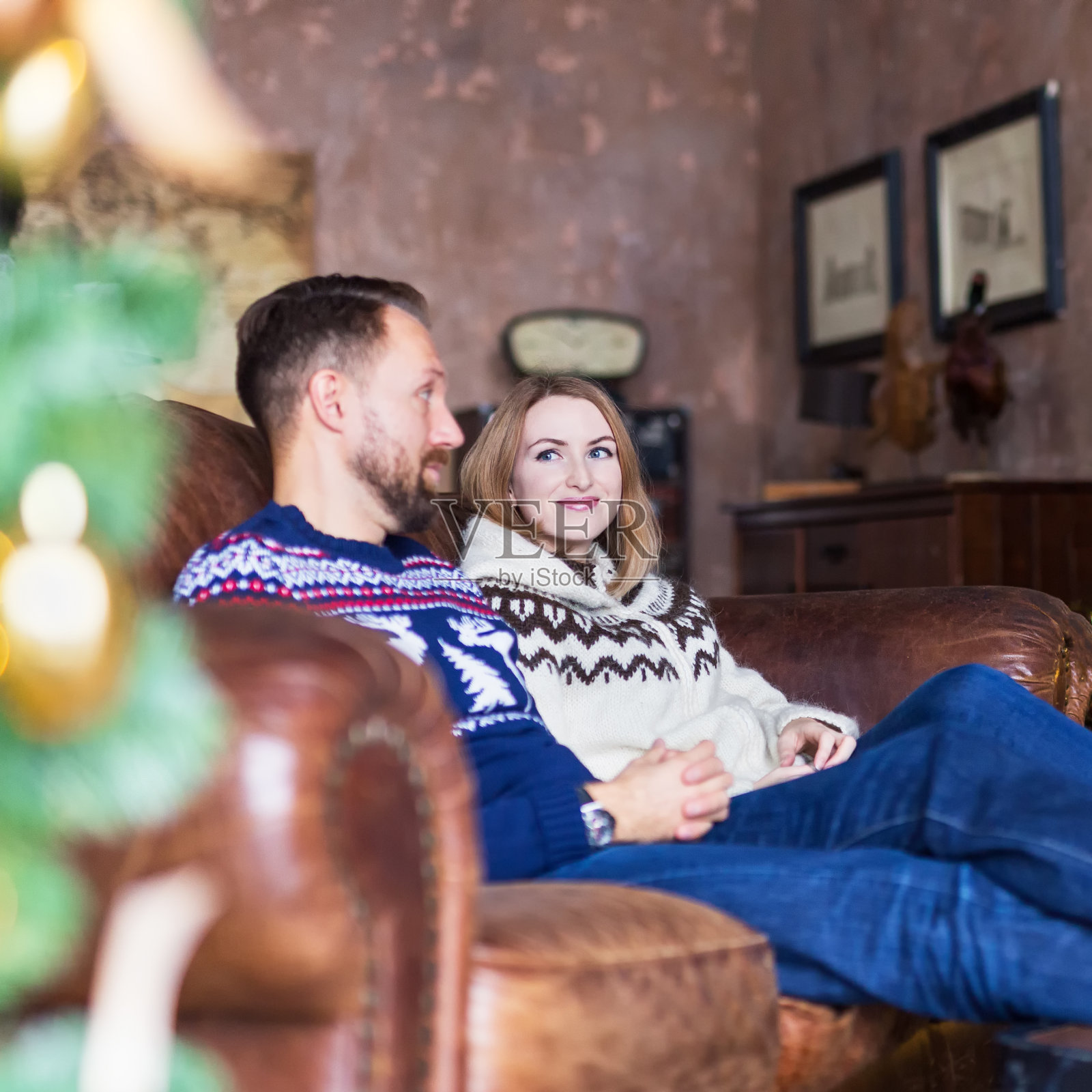 年轻夫妇穿着暖和的运动衫，在阁楼的沙发上休息照片摄影图片