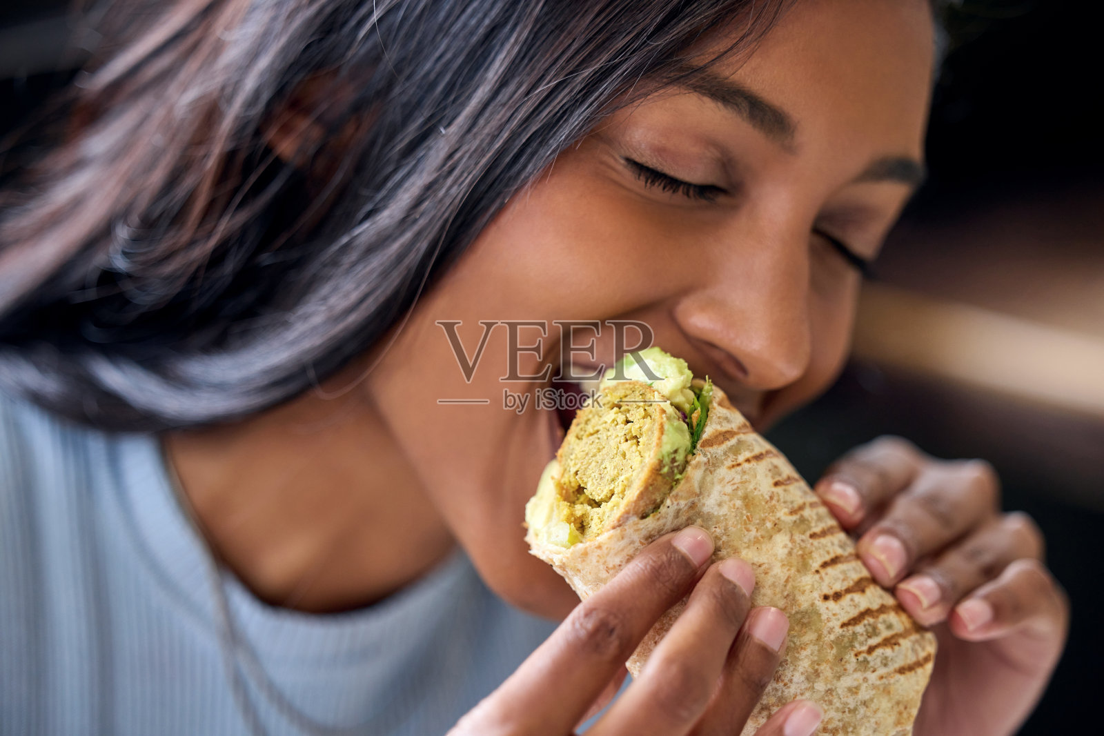 一名年轻女子在午餐时吃着卷饼照片摄影图片