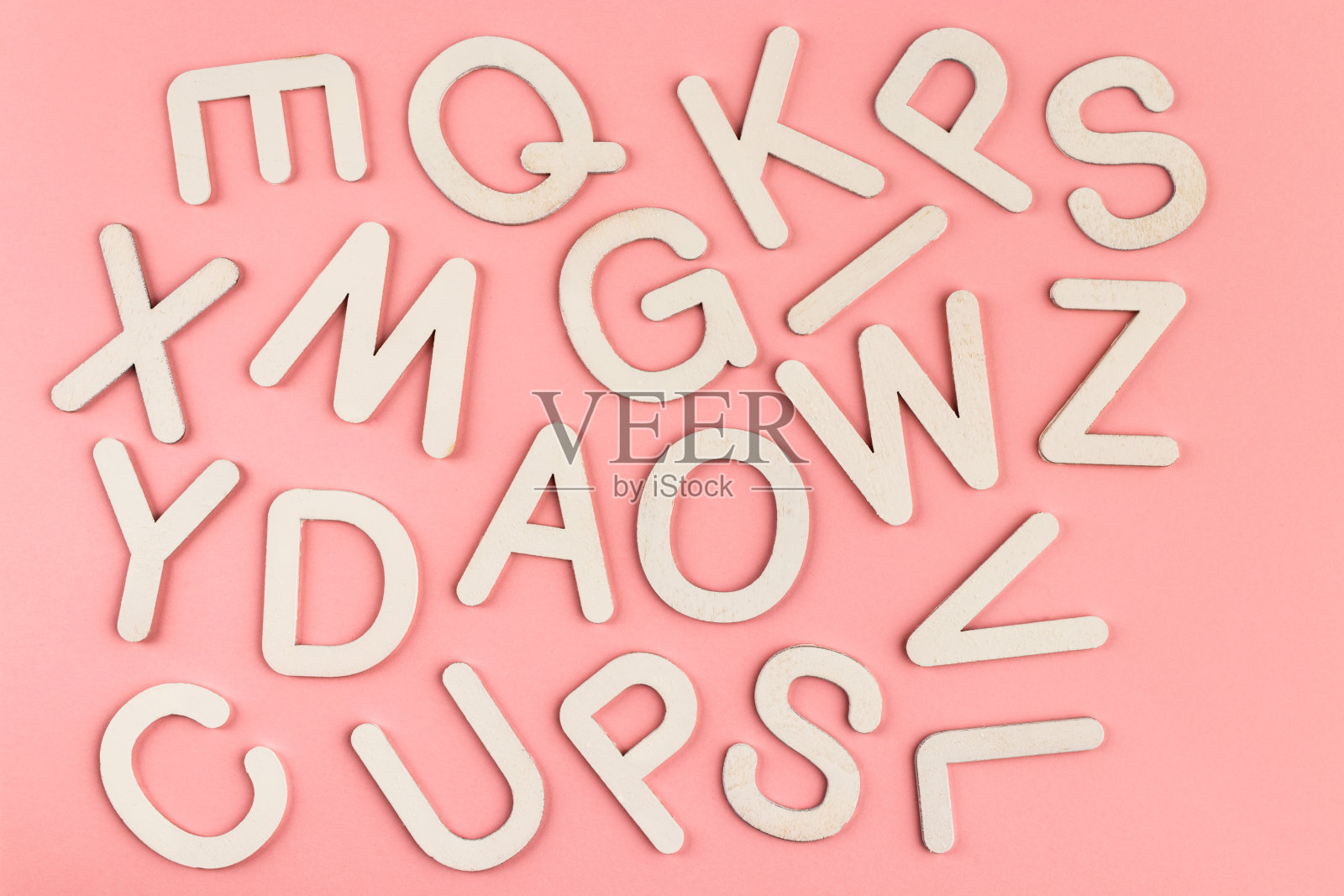 木制字母在粉红色的纸背景上。照片摄影图片