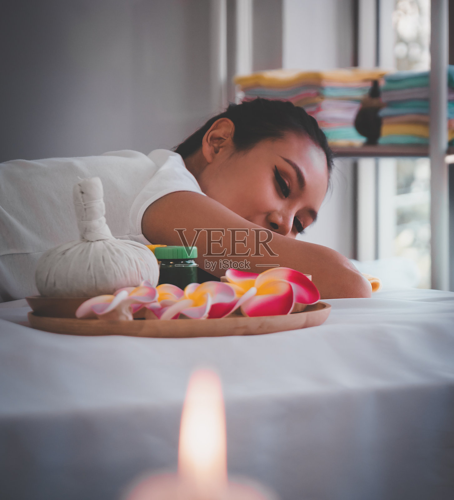亚洲女性放松在泰国温泉与鲜花和热压缩蜡烛照片摄影图片