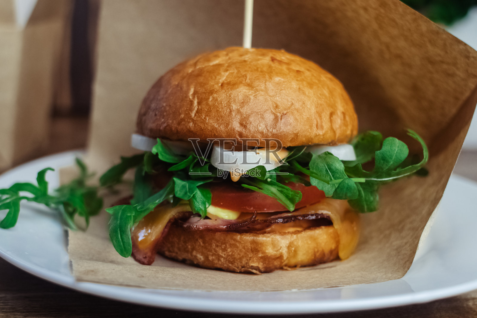 一个标准汉堡的特写镜头。餐馆或咖啡馆里的成人快餐。微距照片的汉堡原料与肉，奶酪和香草。为全家准备的环保汉堡照片摄影图片