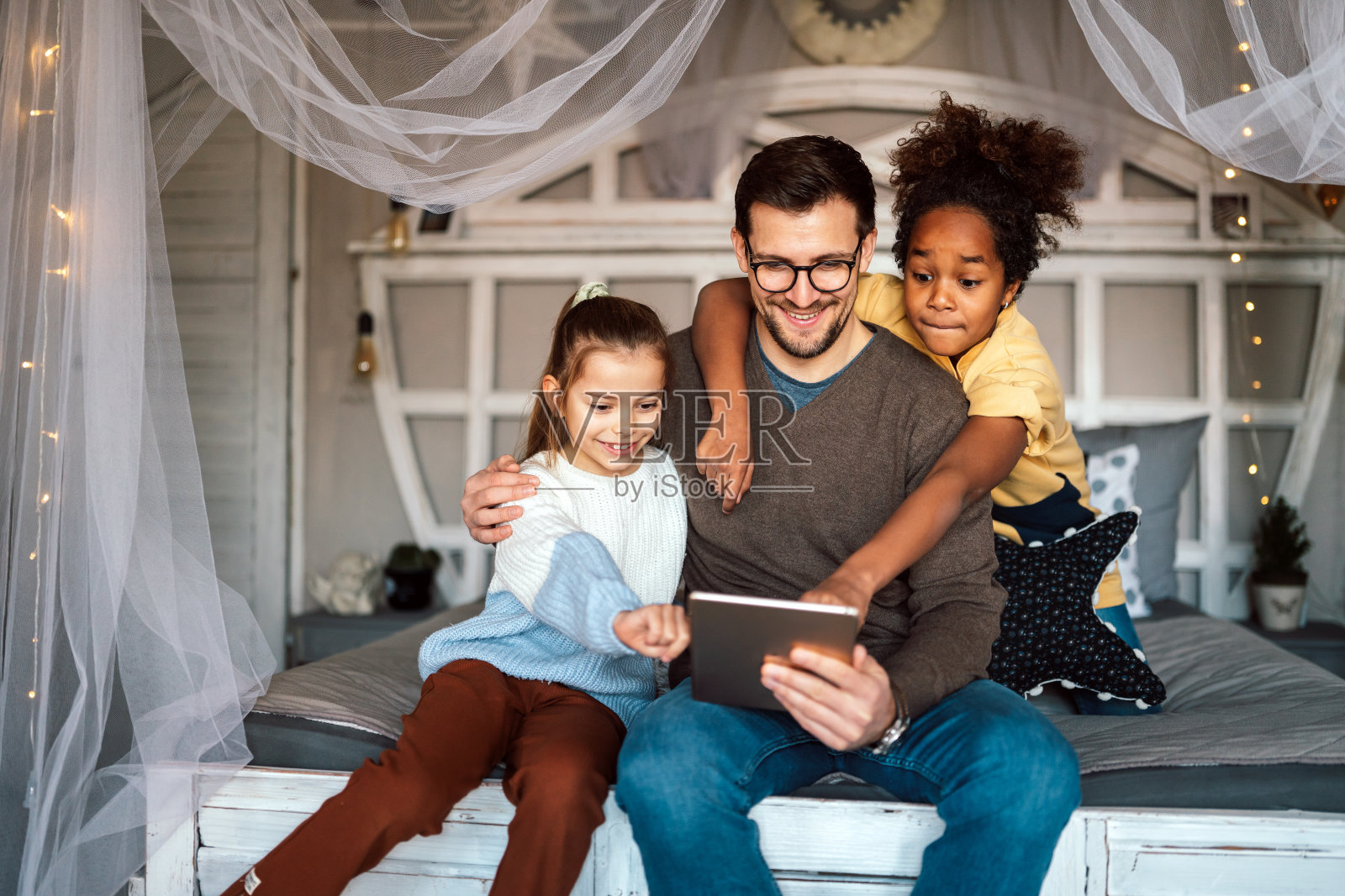 多民族儿童和父亲在平板电脑上玩耍的快乐肖像。技术的家庭概念照片摄影图片