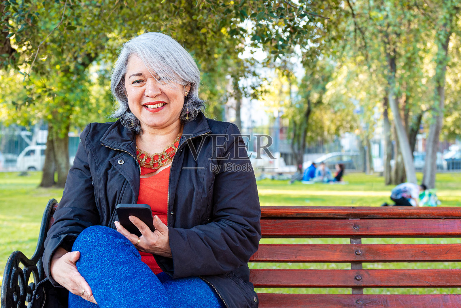 成熟女人在公园里用智能手机照片摄影图片