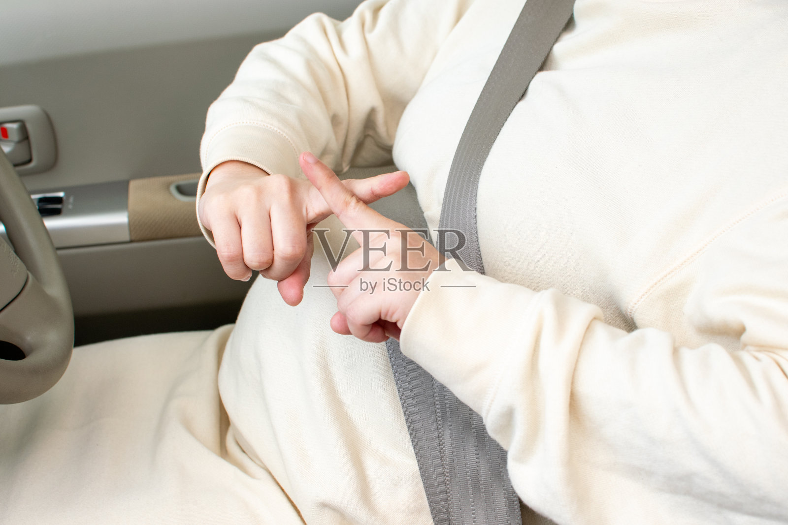 一位年轻的亚洲孕妇不恰当地系了安全带，而且没有留下任何痕迹照片摄影图片