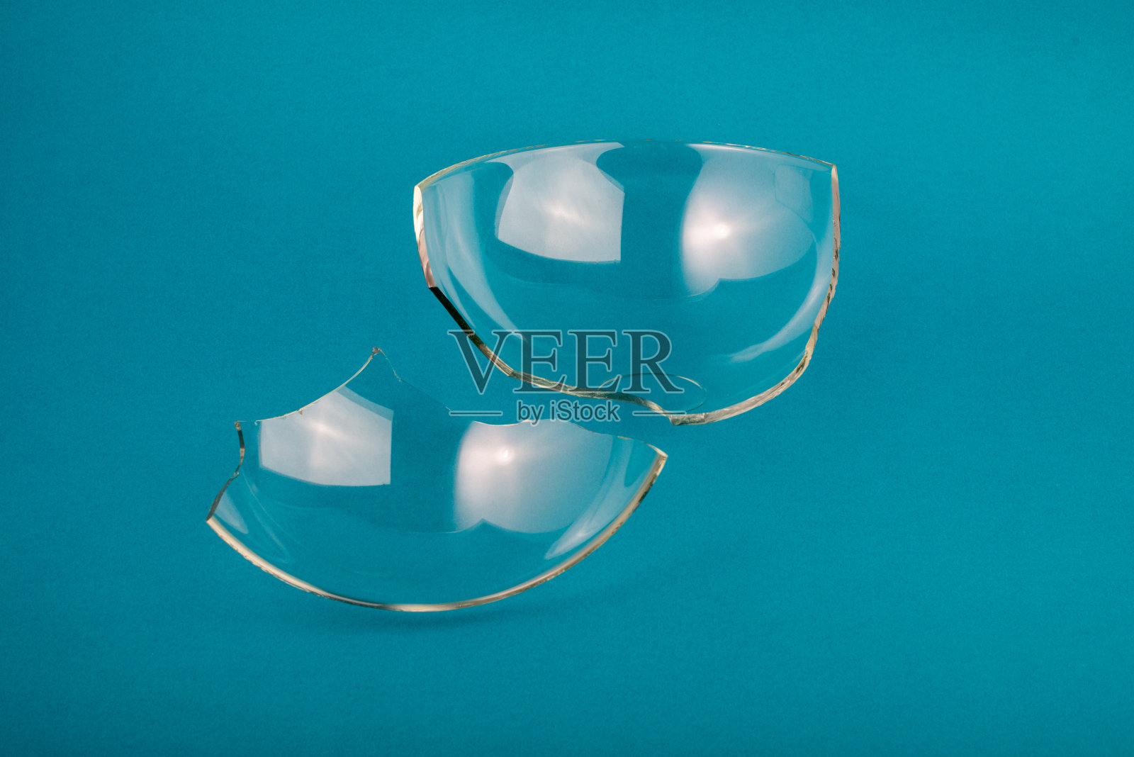 碎玻璃碎片在柔和的蓝绿色背景上。照片摄影图片