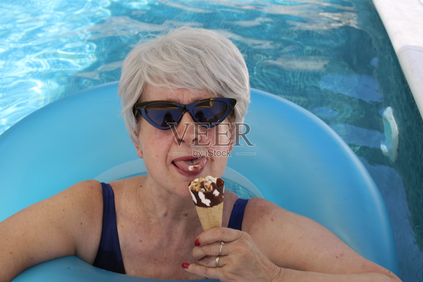 高级游客在游泳池里拿着冰淇淋照片摄影图片