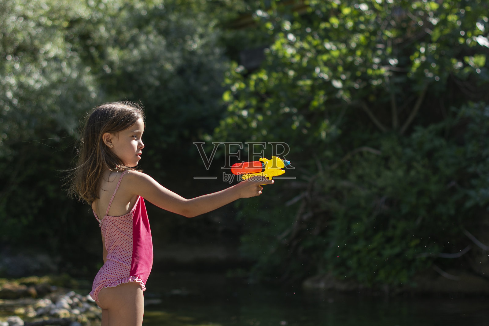 女孩在河里玩着水枪照片摄影图片