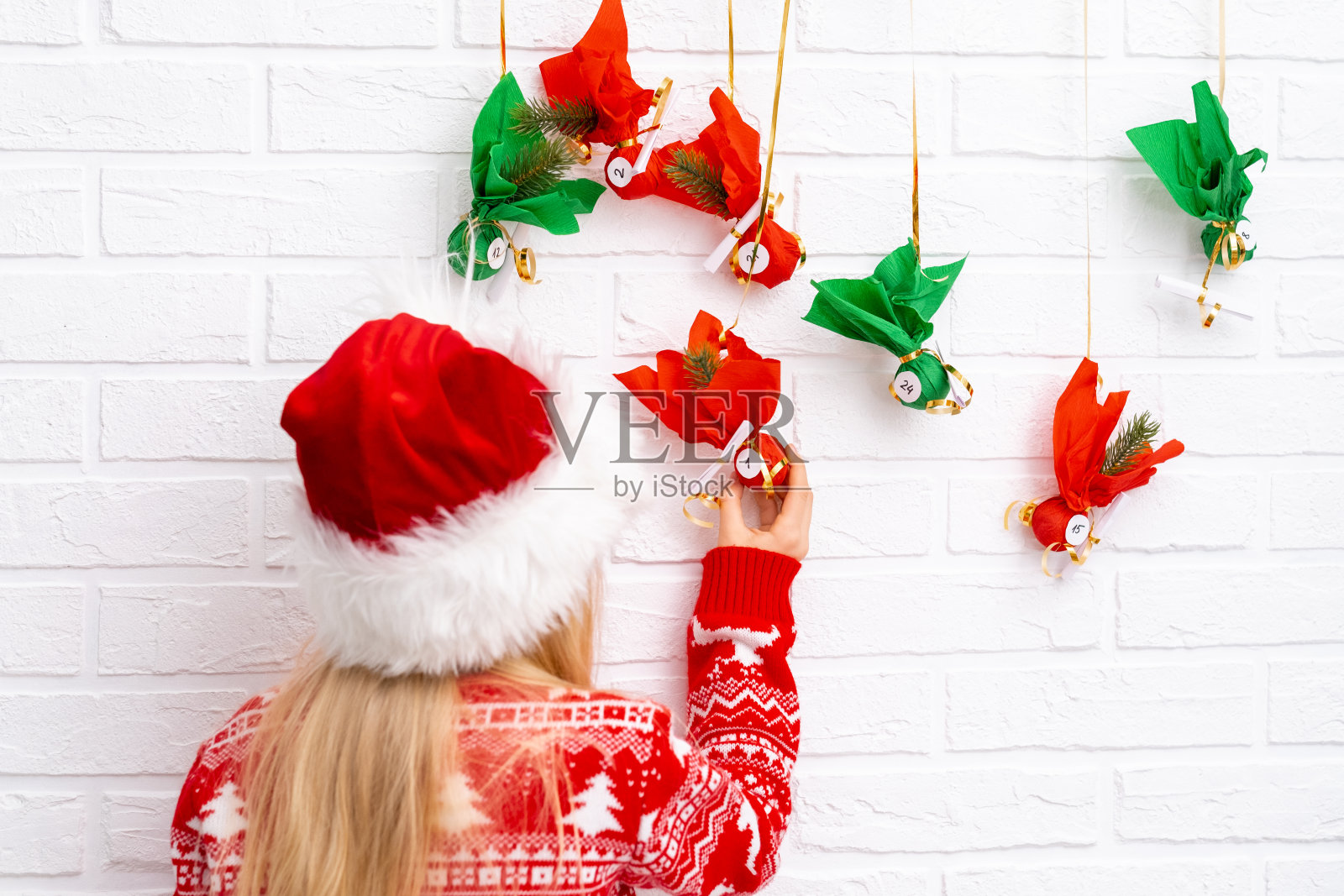 小女孩打开小礼物，惊喜地看到墙上挂着的降临历。快乐等待圣诞节和新年照片摄影图片