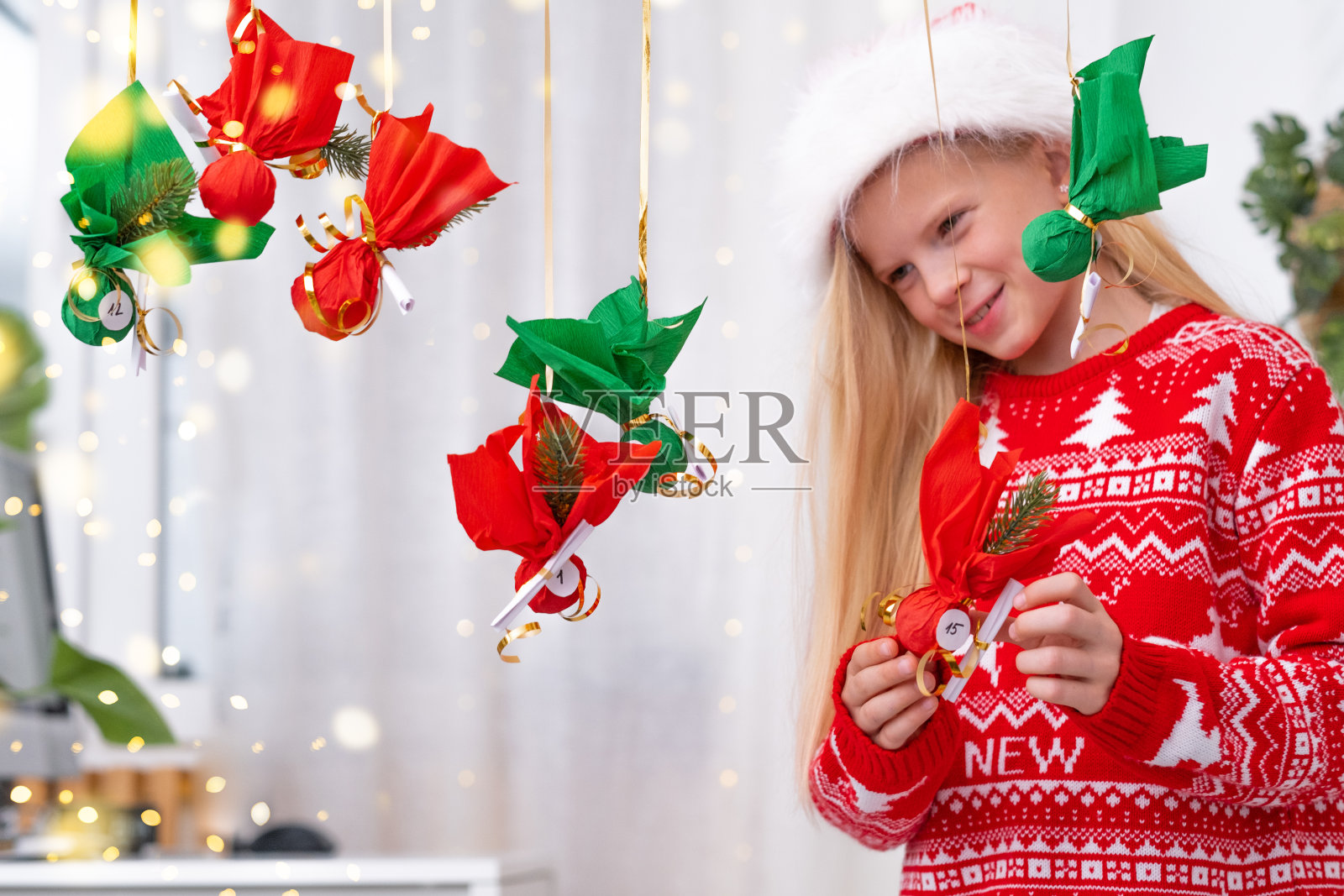 小女孩打开小礼物，惊喜地看到墙上挂着的降临历。快乐等待圣诞节和新年照片摄影图片