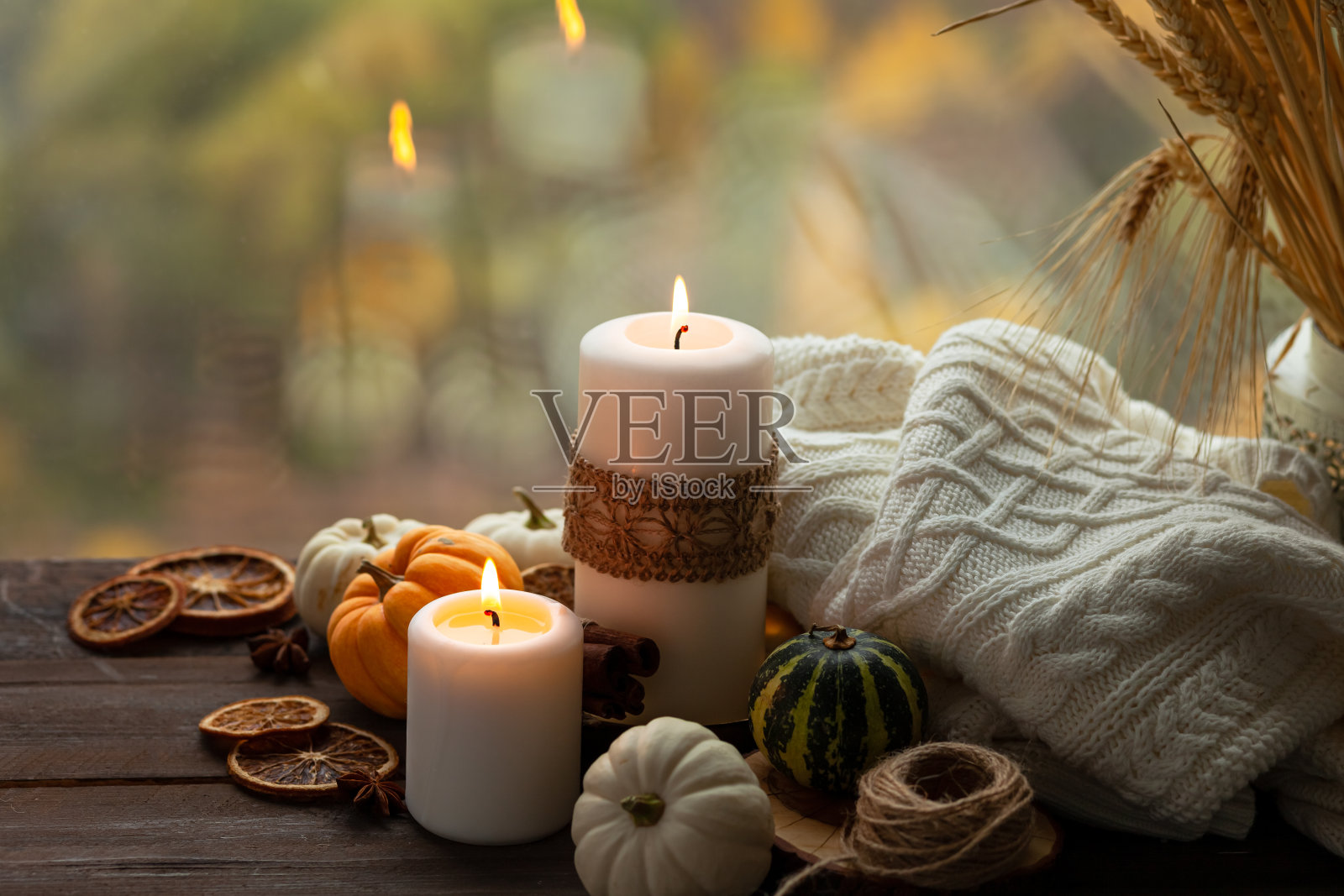秋天的作文与蜡烛，迷你芒奇金南瓜，温暖的羊毛针织格子在木制的风窗台上。深色，低调。温馨的家庭氛围，感恩节的装饰，秋天的色彩。近距离照片摄影图片