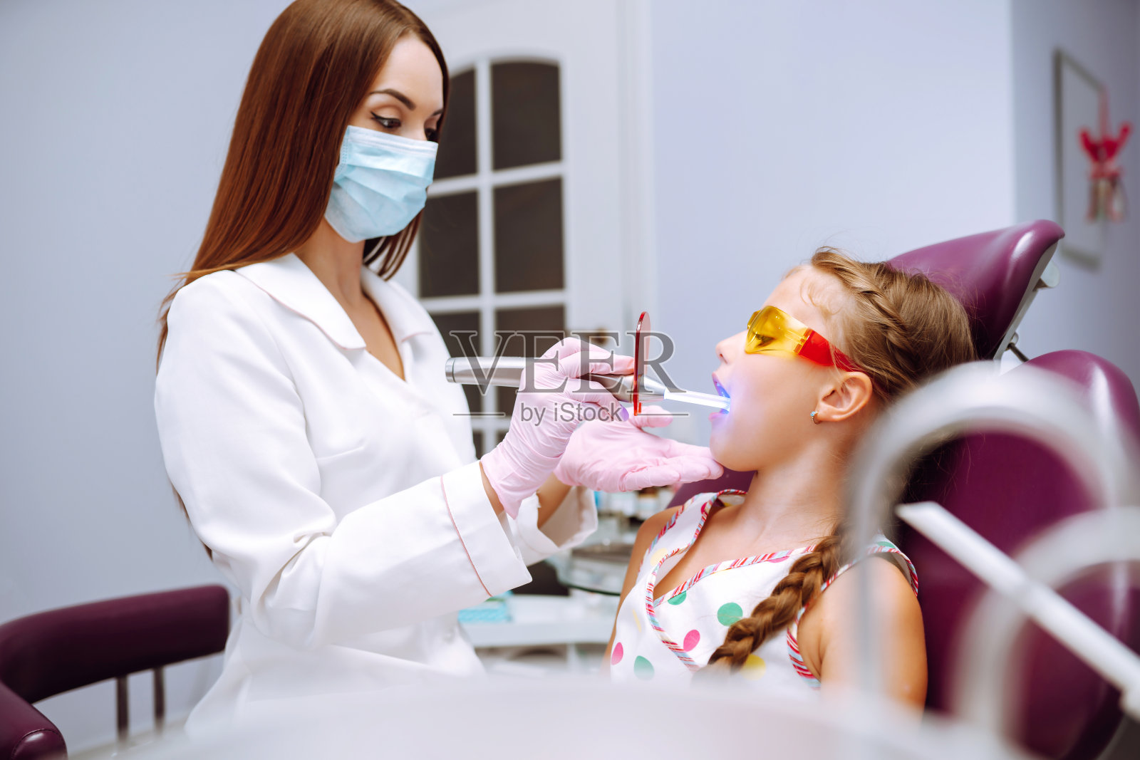 可爱的小女孩在儿科口腔科做完检查后，微笑着与儿科牙医交谈。照片摄影图片