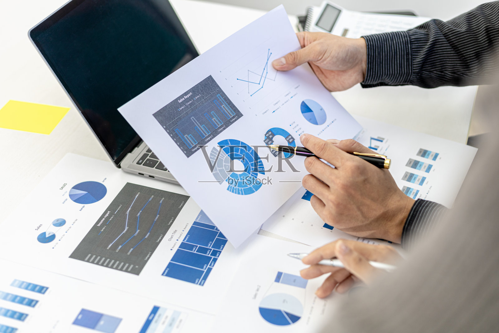 销售部门正在召开月度总结会议，汇报给部门经理，在汇报给经理之前，他们正在核实准备好的文件的正确性照片摄影图片