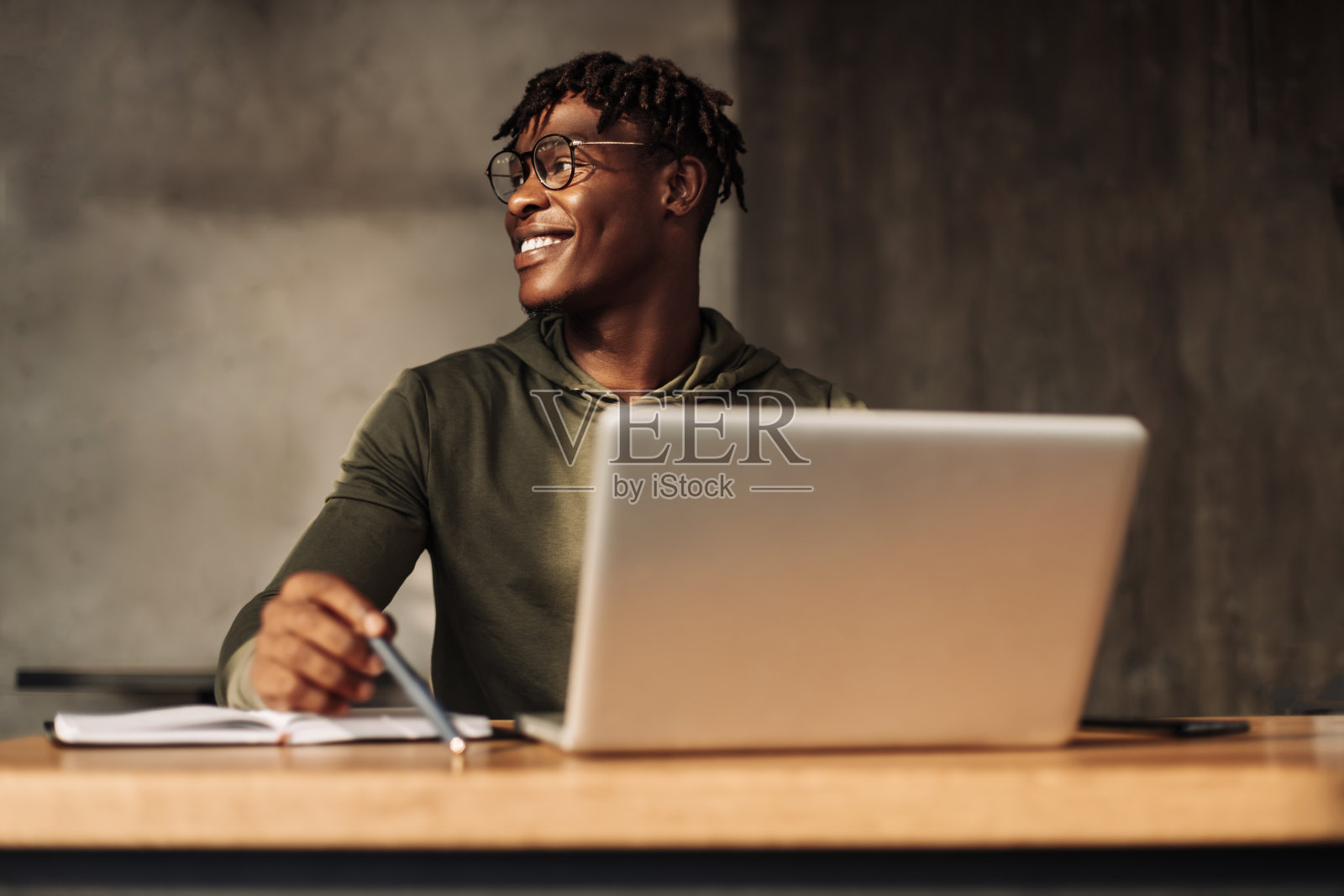 非裔美国人，桌上有笔记本和记事本。一个人用钢笔在笔记本上写字。远程学习照片摄影图片