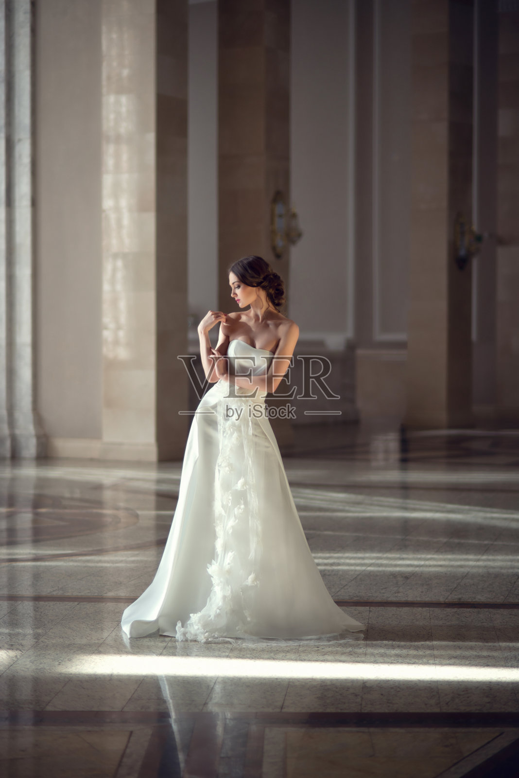 年轻脆弱的黑发女孩。新娘穿着奢华的婚纱在别致的室内与美丽的阳光从窗户婚礼发型和化妆。婚礼盐，美容院照片照片摄影图片