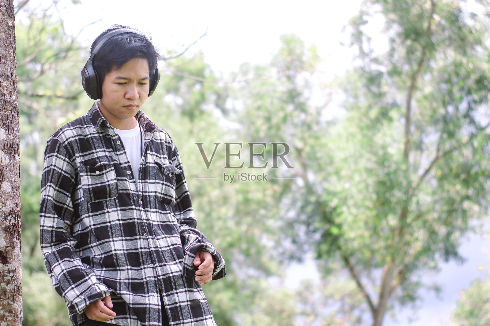 在公园里戴着耳机的年轻人照片摄影图片