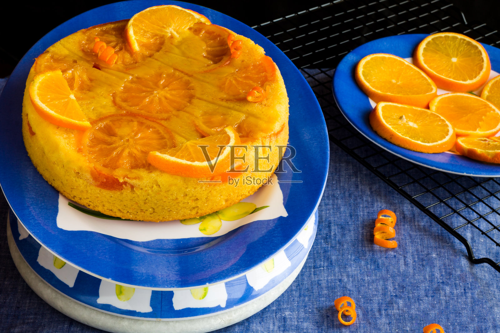 美国颠倒橙色蛋糕或海绵蛋糕与橙色水果切片在蓝色背景的俯视图。湿润的酥皮，上面浇上糖浆。照片摄影图片
